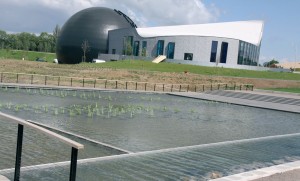 La vue sur Aquarena à partir des nouveaux bassins aquatiques permet de distinguer la ripisylve (formations végétales se développant sur les bords des cours d’eau ou des plans d’eau).