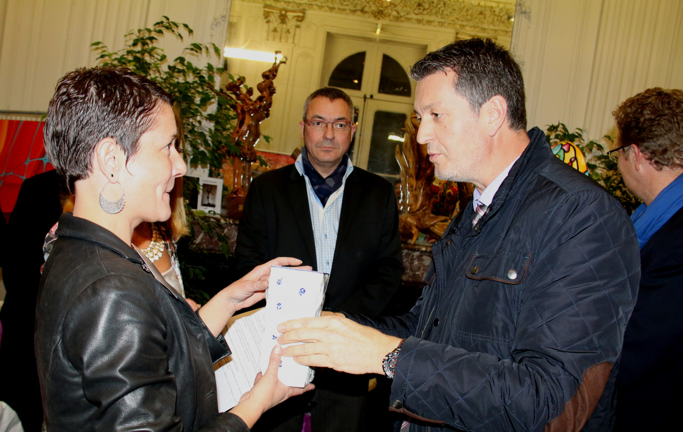 Eric Lorber, directeur du secteur Artois au Crédit Agricole Nord de France, offre une porcelaine d’Arras à Isabelle Diguet en présence de Maurice Ségard en arrière plan (artisan décorateur sur porcelaine qui perpétue la tradition du bleu d’Arras).